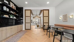 Une cuisine moderne avec un pare-feu en marbre noir, des armoires en bois et un coin repas comprenant une table ronde et des chaises.