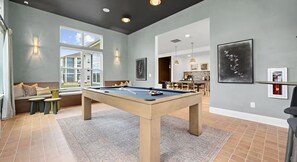A pool table in a room with a large window, a sofa, and a dining area. - 2 King Beds | Pool, Gym & Easy First-Floor Access (Mooresville)