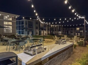 An outdoor patio area with string lights, outdoor seating, and a barbecue grill.