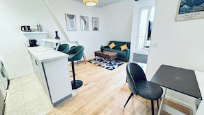 Un espacio habitable compacto con kitchenette, zona de comedor y sala de estar con sofá y sillones.