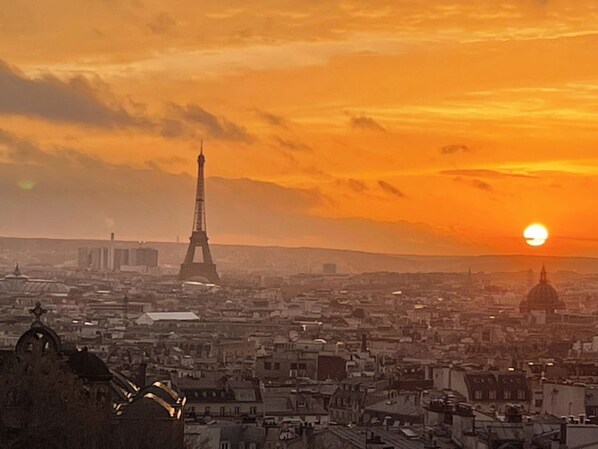 Un paisaje urbano con la Torre Eiffel, una cúpula y edificios bajo un cielo al atardecer.