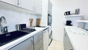 Una cocina moderna con un fregadero, estufa, horno y una cafetera en un estante.