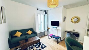 Ein Wohnzimmer mit einer Couch, einem Couchtisch, einem Fernseher und einem kleinen Beistelltisch.