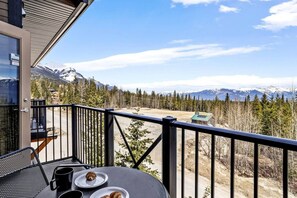A balcony with a table, chairs, and a view of snow-capped mountains. - Cozy Mountain Loft Ski-in/out+Hot Tub Sleeps 6 (Golden)