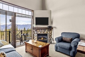 A living room with a fireplace, a sofa, a coffee table, and a TV mounted on the wall.