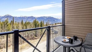 A balcony with a table and chairs, overlooking a mountain range.