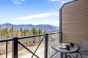 A balcony with a table and chairs, overlooking a mountain range. - Cozy Mountain Loft Ski-in/out+Hot Tub Sleeps 6 (Golden)