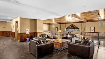 A spacious lobby with leather sofas, a coffee table, and a wooden ceiling.