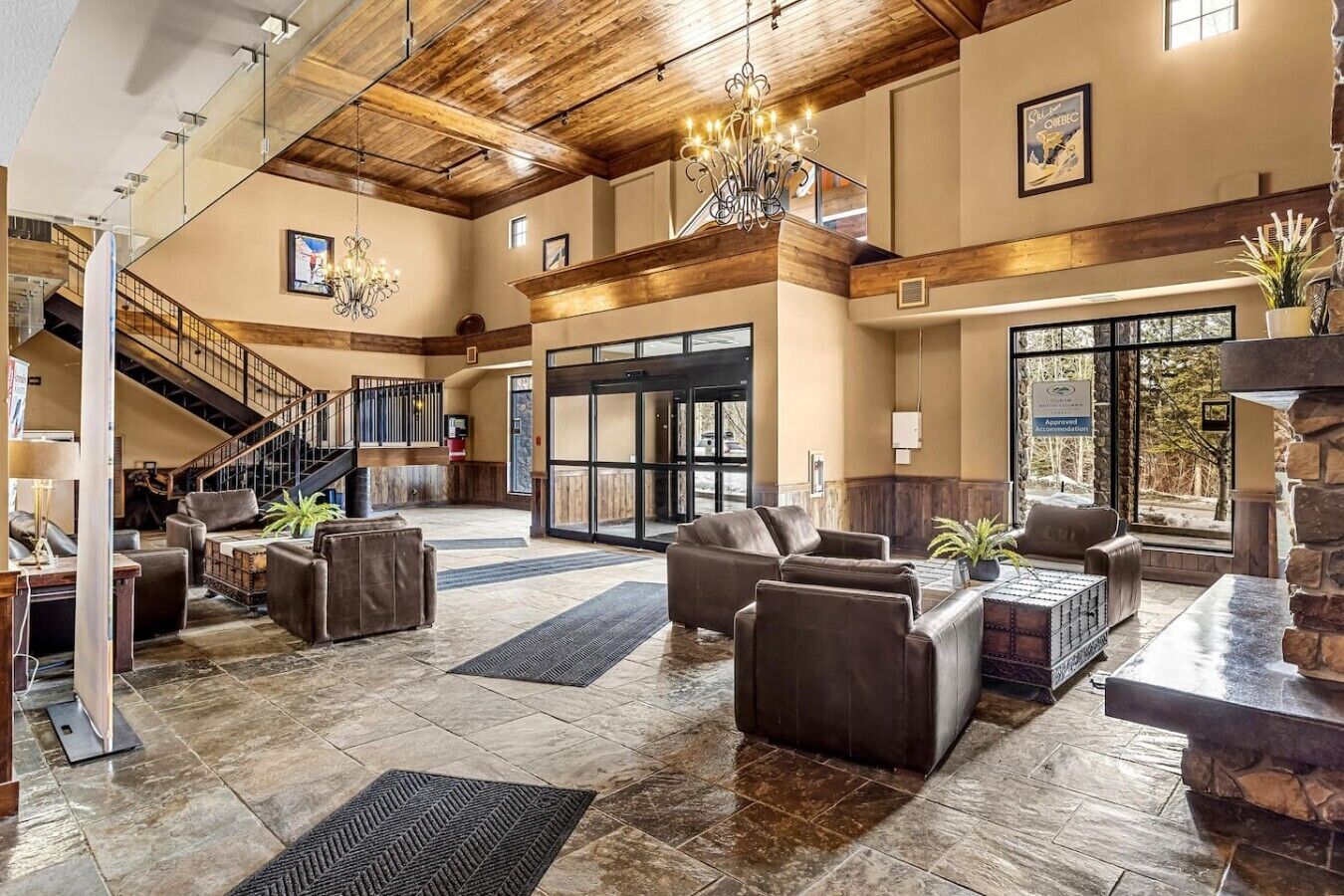 A spacious lobby with leather sofas, a chandelier, and a staircase.
