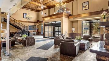 A spacious lobby with leather sofas, a chandelier, and a staircase.