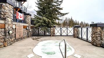 A stone-walled spa area with a hot tub, a flag, and a clock.