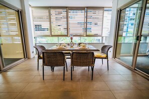 A dining area with a table set for four, wicker chairs, and a view through large windows. - Luxury 2 BR | Pool Gym Parking Sydney CBD getaway (Camperdown)