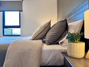 A neatly made bed with pillows and a potted plant on a bedside table. - Downtown Santiago Oasis: Rooftop Pool, Cowork Space & Sunset Balcony (Santiago)