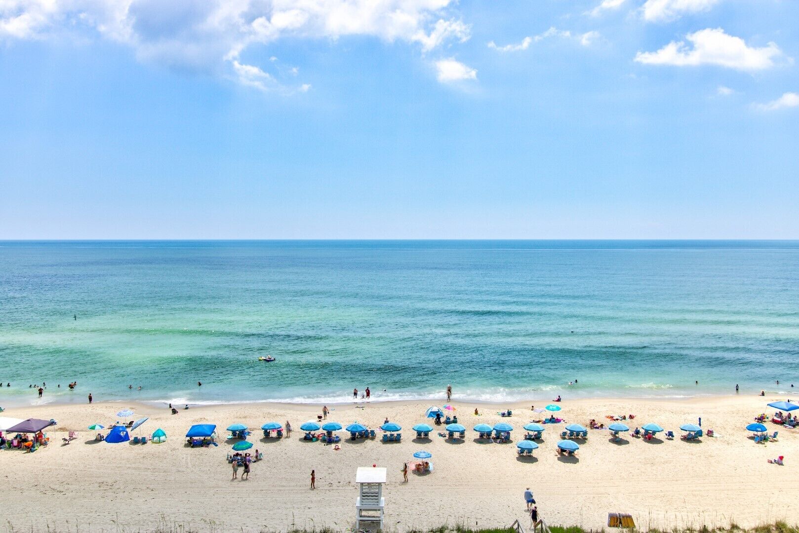 Ein Strand mit Sonnenschirmen und Menschen.