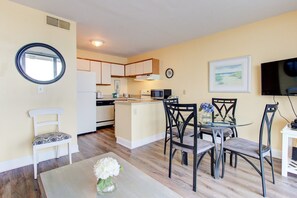 A compact living space with a dining area, kitchen, and a TV. - Oceanfront 1 Bedroom Condo in Carolina Beach 0808 (Carolina Beach)