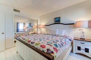 Ein Schlafzimmer mit einem Bett, Nachttischen, einem Spiegel und einem Beistelltisch.