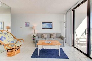 Ein Wohnzimmer mit einer Couch, einem Holzstuhl, einem Couchtisch und einer großen Schiebeglastür.
