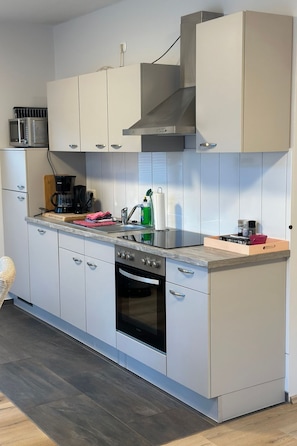 A modern kitchen with white cabinets, a stainless steel range, a built-in oven, and a microwave. - FEWO „Am Stausee“ by Interhome (Friesoythe)