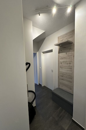 A hallway with a wooden accent wall, a door, and a staircase leading to another room. - FEWO „Am Stausee“ by Interhome (Friesoythe)