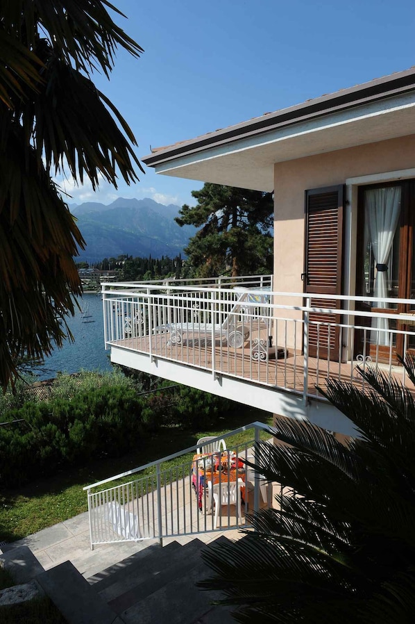 A balcony with a view of a lake and mountains, a white railing, and a door with a window. - Holiday flat with a view of the Bay of Val di Sogno (Malcesine)