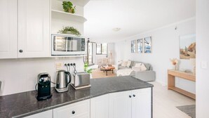 Una cocina moderna con armarios blancos, microondas integrado y cafetera.