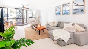 Un salón amplio con un sofá gris, una mesa de centro y un balcón con vistas.