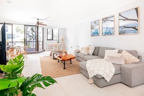 Ein großzügiger Wohnbereich mit grauem Sofa, einem Couchtisch und einem Balkon mit Blick.