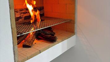 Una chimenea con rejilla metálica y leña encendida.