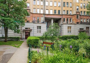 A courtyard with a bench, greenery, and a building with multiple windows and balconies. - Żelazna Urban Comfort Apartment (Warszawa)