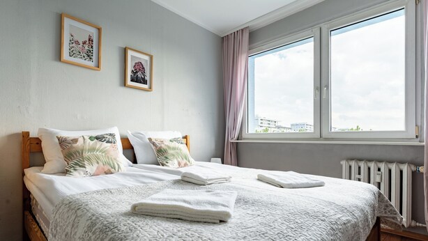Un dormitorio con una cama grande, una ventana con cortinas y dos cuadros en la pared.