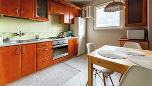 Una cocina con armarios de madera, una estufa, un refrigerador y una mesa de comedor con sillas.