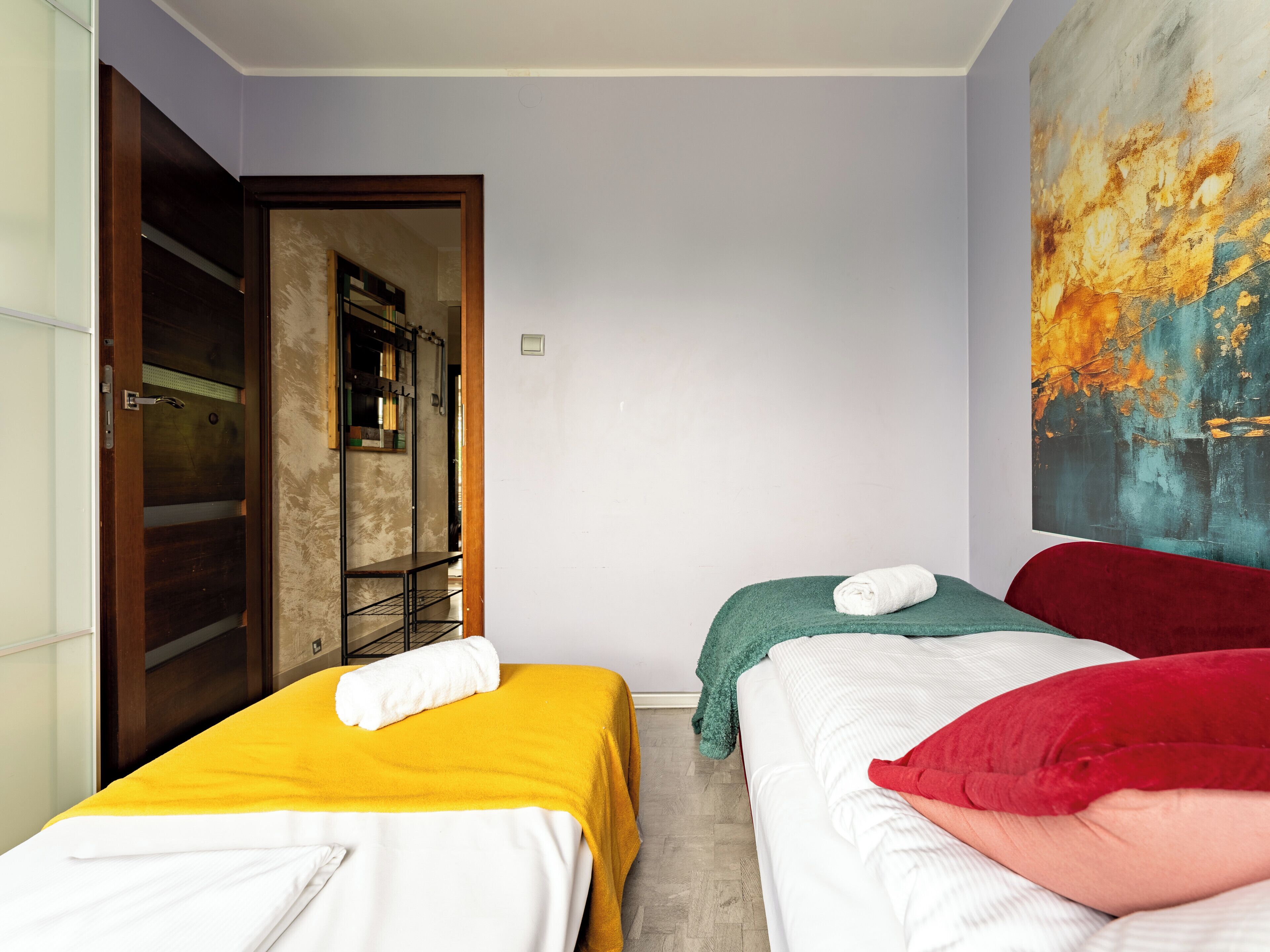 Une chambre d’hôtel avec deux lits, une porte en bois, un tableau au mur et une petite table avec une chaise.