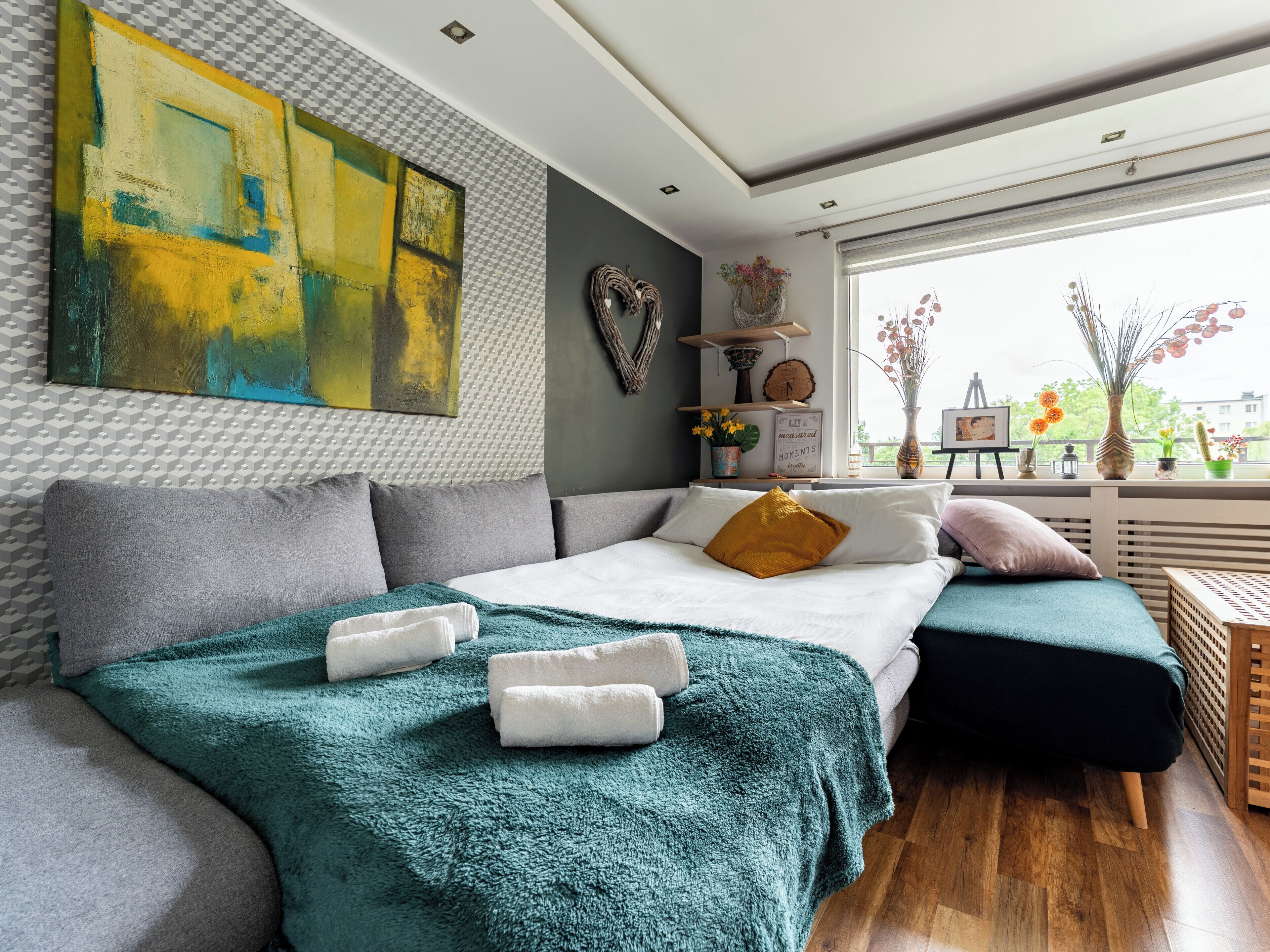 Une chambre moderne avec un grand lit, une vue sur la ville et un grand tableau abstrait accroché au mur.
