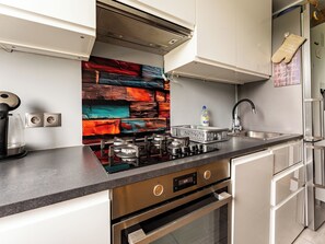 A modern kitchen with a gas stove, a built-in oven, a stainless steel sink, and a decorative backsplash.