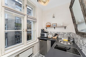 Eine kleine Küche mit Fenster, einer Mikrowelle, einem Spülbecken und einer Arbeitsplatte.