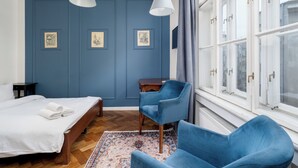 Une pièce comprenant un lit, une chaise, un bureau et une fenêtre avec des rideaux.