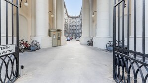 Un couloir avec une grille, des vélos et des voitures garées.