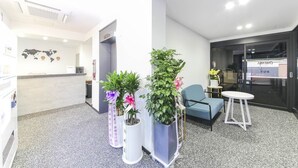 A reception area with a desk, chairs, potted plants, and a glass door leading to a room. - Gwangju Hotel Lantana - Hanam (Gwangju)