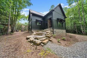 Eine rustikale Holzhütte mit einer Steintreppe, die zum Eingang führt, umgeben von einem Wald.