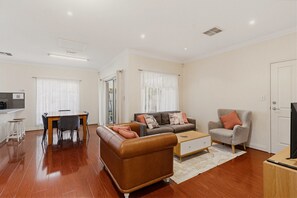 Un salon moderne comprenant un canapé, un fauteuil, une table basse et un coin repas.