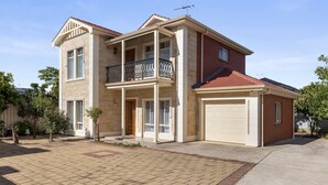 A two-story house with a balcony, garage, and a paved driveway. - Family-friendly 4-bed Home With Parking (Adelaide)