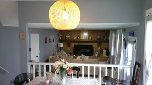 A living room with a fireplace, a dining area with a table set for two, and a staircase leading to another level.