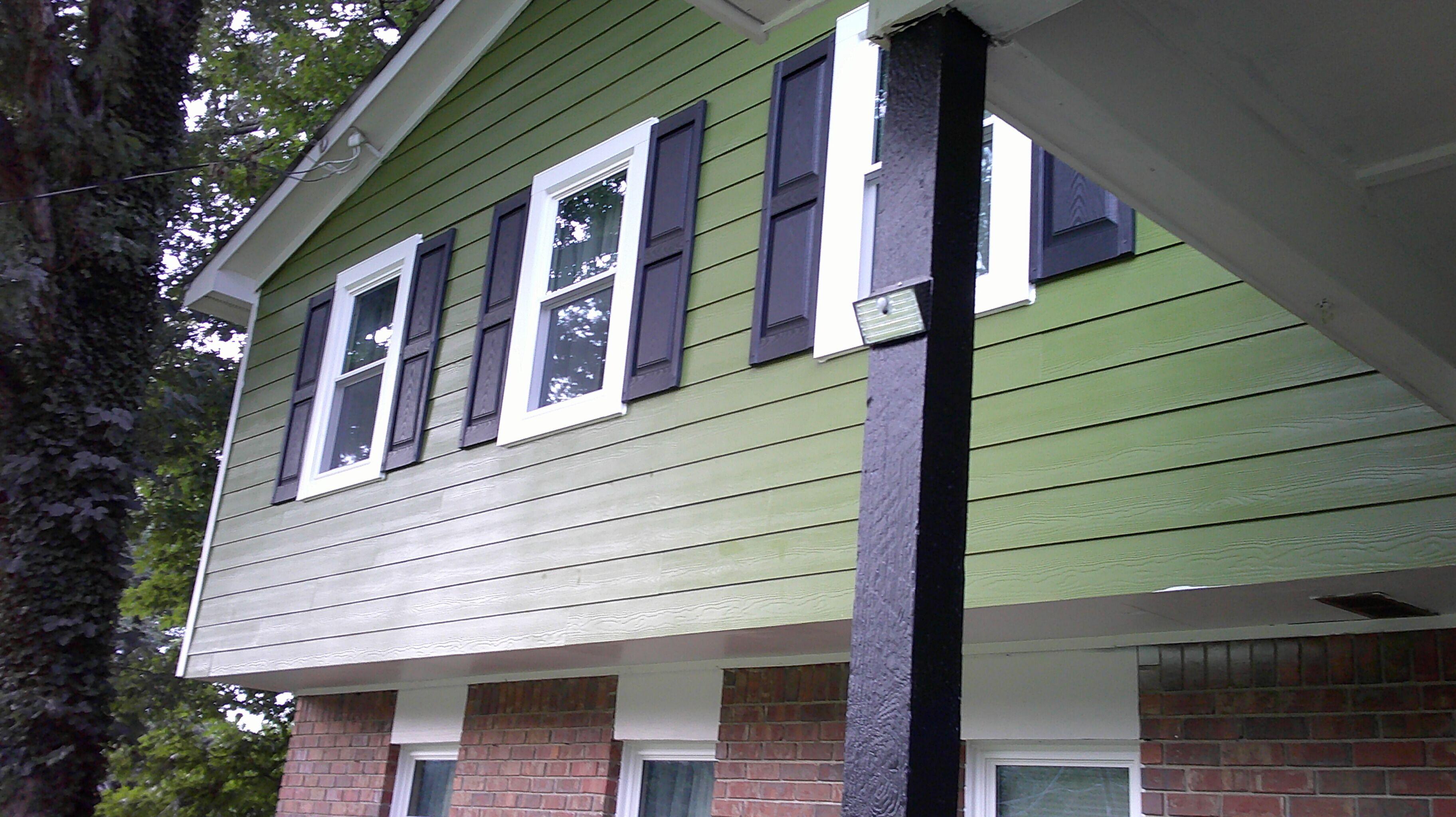 A two-story house with a green exterior, white trim, and dark shutters.