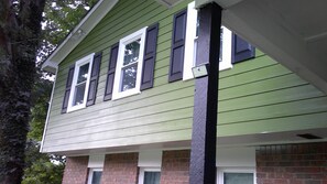 A two-story house with a green exterior, white trim, and dark shutters.