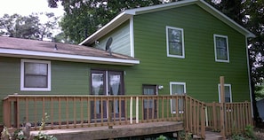 A two-story house with a green exterior, a wooden deck, and a satellite dish.