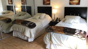 A hotel room with two beds, each with white bedding and a brown throw blanket. There are bedside tables with lamps and a phone. The room has a large mirror and abstract art on the walls. - Suite F, 2BR / 2BA in San Pedro Garza García, Centrito Valle (San Pedro Garza García)