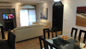 A modern living room with a sofa, dining table, chairs, and a TV. - Suite F, 2BR / 2BA in San Pedro Garza García, Centrito Valle (San Pedro Garza García)