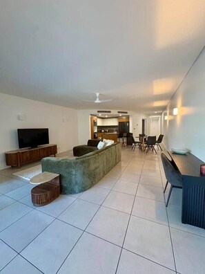 Ein modernes Wohnzimmer mit Sofa, Fernseher und Essbereich.