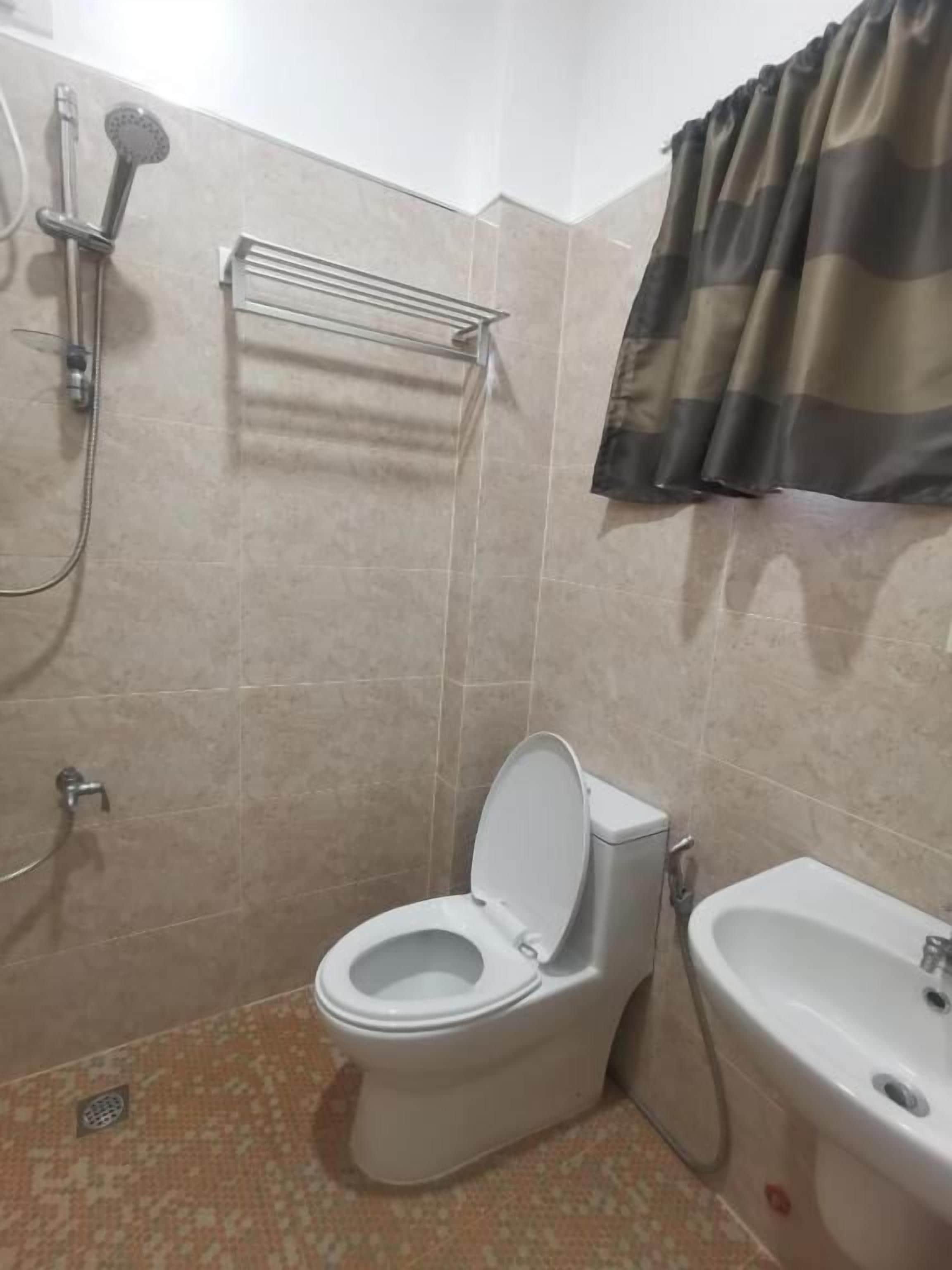 A bathroom with a toilet, bidet, shower, and towel rack.