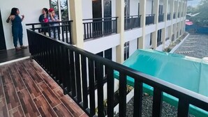 Un edificio de varios pisos con balcones, un espacio exterior cubierto y una piscina.